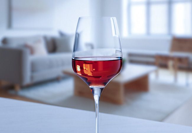 Бокал с розовым вином стоит на белой мраморной столешнице в светлой современной гостиной